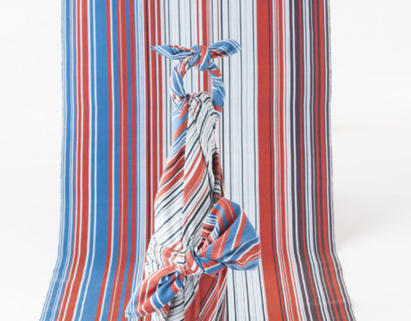 青赤黒白の細かいストライプの布と同じテキスタイルで作った風呂敷でボトルを包んでいる